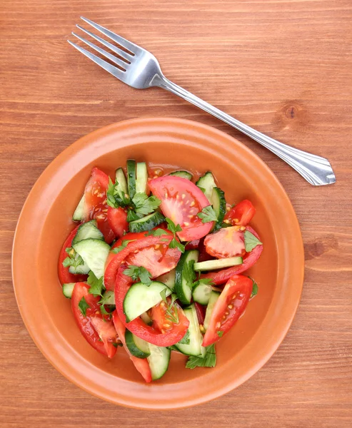 Свіжий салат з помідорами та огірками на дерев'яному фоні — стокове фото