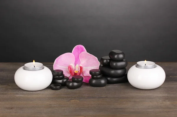 Spa kövek orchidea virágot és gyertyát a fából készült asztal-szürke háttér — Stock Fotó