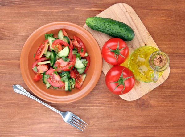 Salade fraîche avec tomates et concombres sur fond de bois — Photo