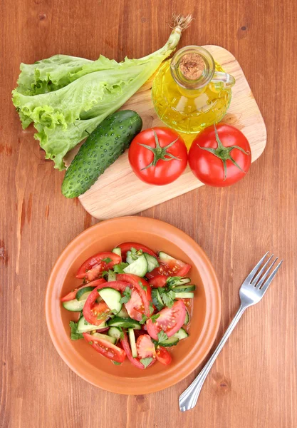 Fresh salad with tomatoes and cucumbers on wooden background — Stock Photo, Image