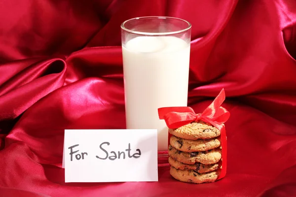 Vaso de leche y galletas sobre fondo de tela roja — Foto de Stock