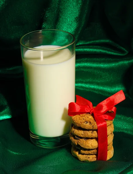 Glas melk en koekjes op groene doek achtergrond — Stockfoto