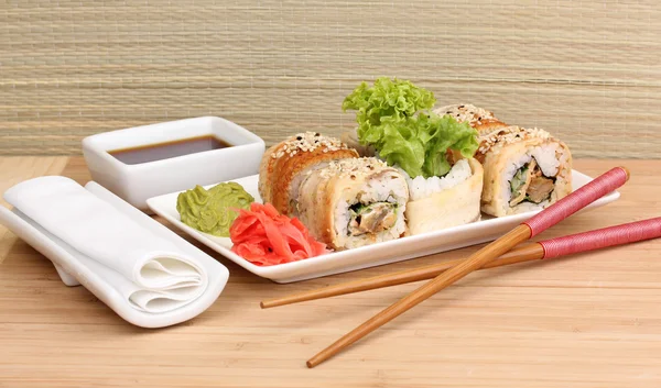Lezzetli rulo ile chopsticks açık renkli ahşap tablo üzerinde beyaz tabakta servis — Stok fotoğraf