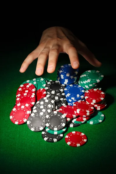 Poker chips and hand above it on green table — Stock Photo, Image
