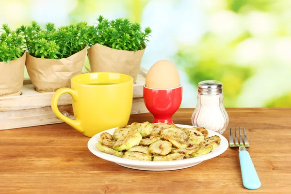 Fried zucchini with eggs and coffee for breakfast on wooden table on green background — Stock Photo, Image