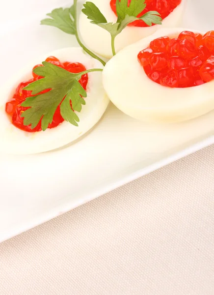 Красная икра в яйцах на белой тарелке на ткани — стоковое фото