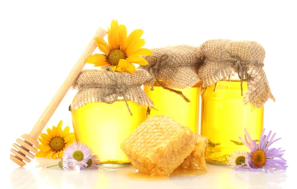 Süßer Honig in Gläsern mit Waben, hölzernem Nieselregen und Blüten isoliert auf weiß — Stockfoto