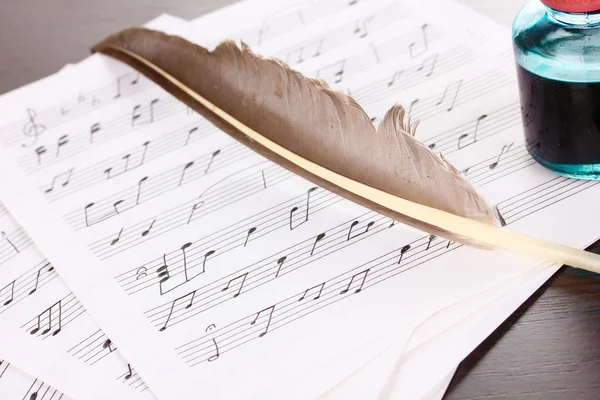 Музичні ноти і перо на дерев'яному столі — стокове фото