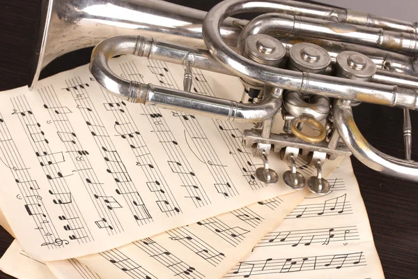 Notas musicais e trompete na mesa de madeira — Fotografia de Stock