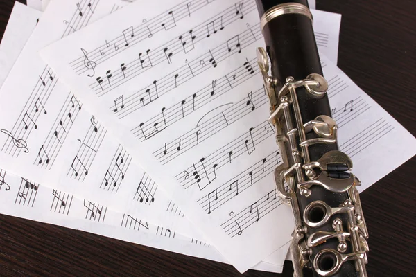 Notas musicales y clarinete sobre mesa de madera — Foto de Stock