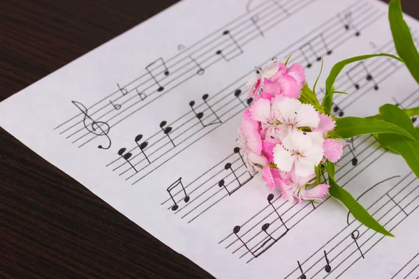 Notas musicais e flor na mesa de madeira — Fotografia de Stock