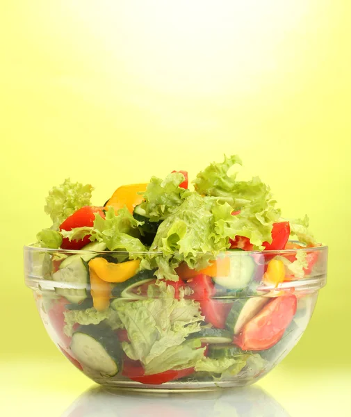 Frischer Gemüsesalat in transparenter Schüssel auf grünem Hintergrund — Stockfoto