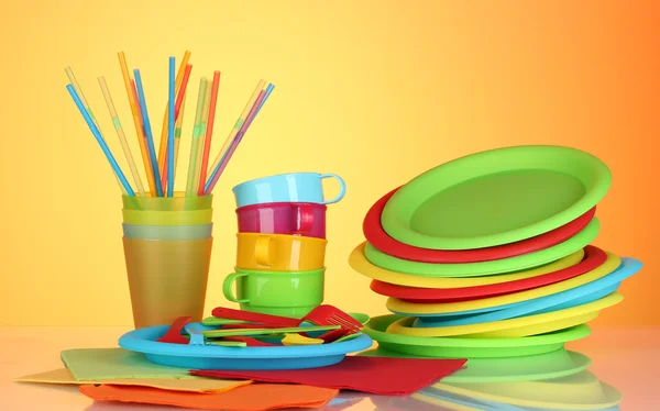 Světlé plastové jednorázové nádobí na barevné pozadí — Stock fotografie