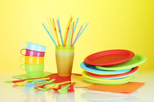Utensílios de mesa descartáveis de plástico brilhante no fundo colorido — Fotografia de Stock
