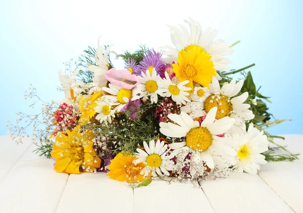 Güzel mavi zemin üzerine ahşap masa üzerinde parlak kır çiçekleri buketi — Stok fotoğraf