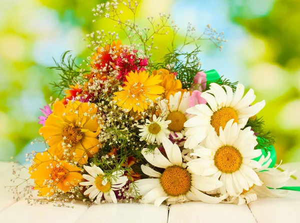 Bellissimo bouquet di fiori di campo luminosi, su tavolo di legno su sfondo verde — Foto Stock