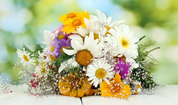 Vacker bukett av ljusa blommor, på träbord på grön bakgrund — Stockfoto