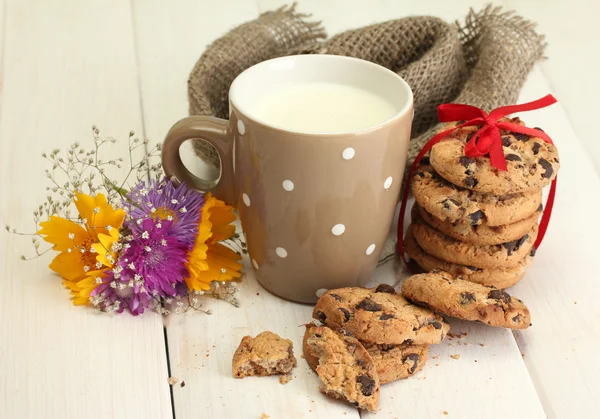 喝杯牛奶，巧克力芯片与红丝带和野花的 cookie 在绿色背景上的木桌上 — 图库照片