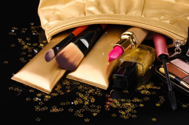 Beautiful golden makeup bag and cosmetics isolated on black clipart