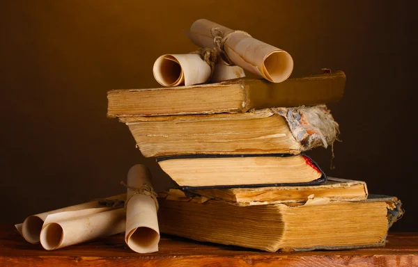 Stapel alter Bücher und Schriftrolle auf braun — Stockfoto