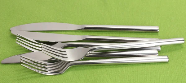 Вилки та ножі на зеленій скатертині — стокове фото