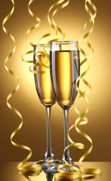 Glas champagne och streamer på gul bakgrund — Stockfoto
