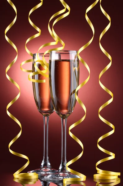 Glazen van champagne en streamer op rode achtergrond — Stockfoto