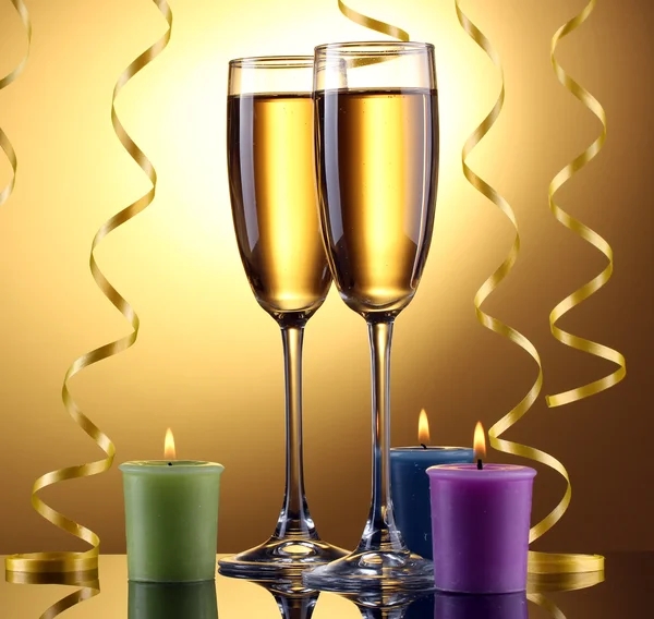 Copos de champanhe, velas e streamer no fundo amarelo — Fotografia de Stock