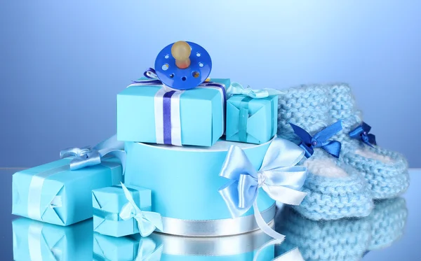 Hermosos regalos, bootees de bebé y maniquí sobre fondo azul — Foto de Stock