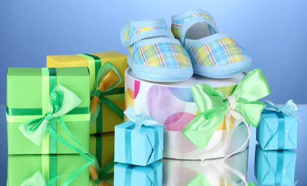 Prachtige cadeaus en baby's bootees op blauwe achtergrond — Stockfoto