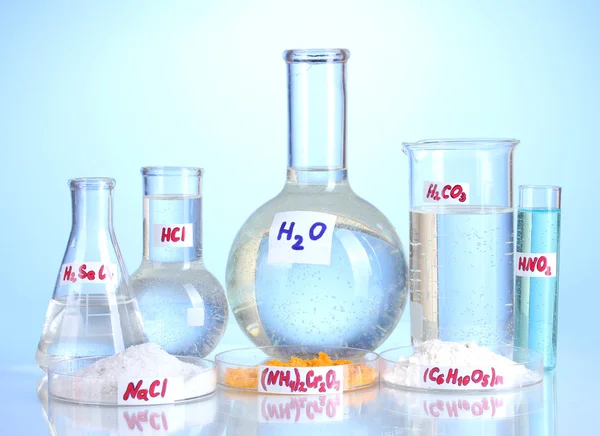 Probówki z różnych kwasów i środków chemicznych na niebieskim tle — Zdjęcie stockowe