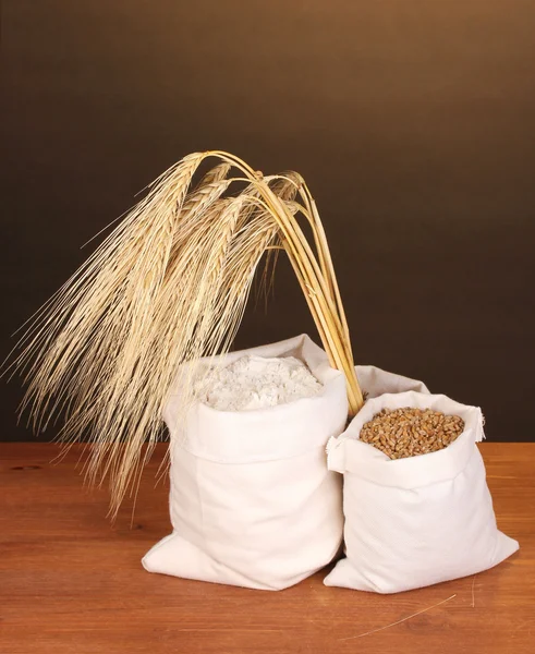 Farine et grain de blé sur table en bois sur fond sombre — Photo