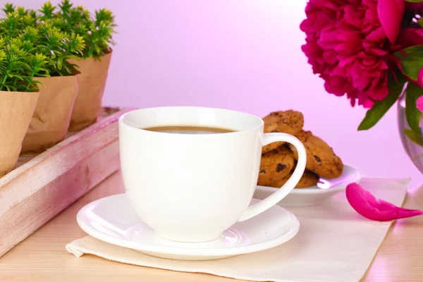 Kopp kaffe, kakor och blommor på bord i café — Stockfoto