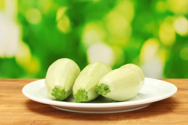 Squash in white plate on wooden table on green background close-up — Stock Photo, Image