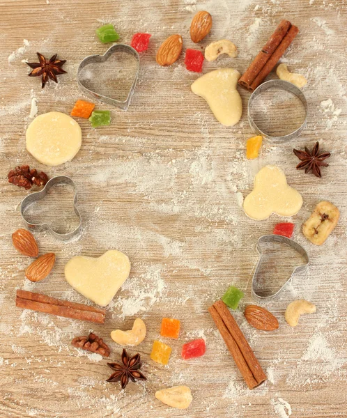 Frame made of candied fruit, nuts, unbaked biscuits and molds for cookies on a wooden table close-up — Stock Photo, Image