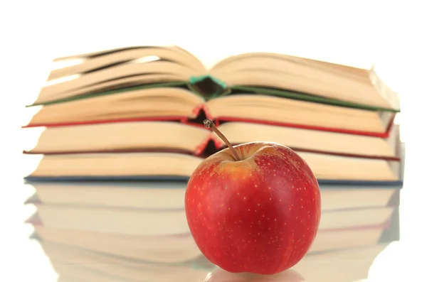 Стопка открытых книг с яблоком на белом фоне крупным планом — стоковое фото