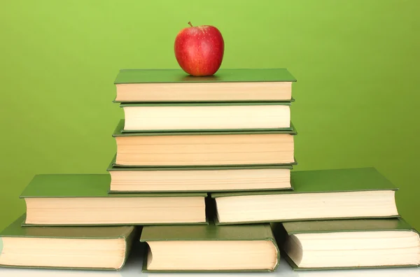 Куча книг с яблоком на зеленом фоне крупным планом — стоковое фото