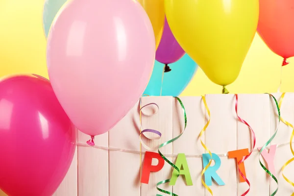 Party. Luftballons gegen einen Holzzaun auf gelbem Hintergrund — Stockfoto