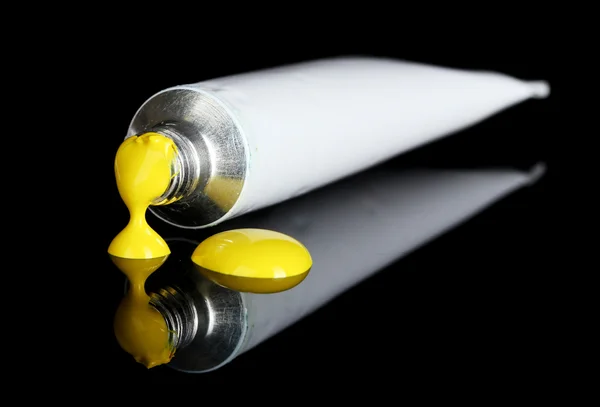 Tinta amarela segue do tubo no fundo preto close-up — Fotografia de Stock