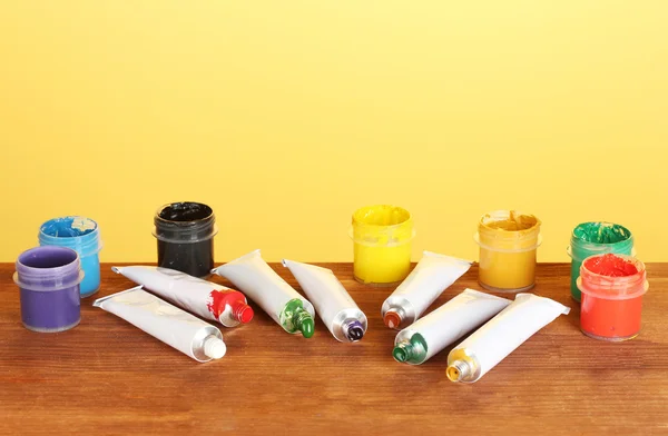 Tubes avec aquarelles colorées et bocaux avec gouache sur table en bois sur fond lumineux — Photo