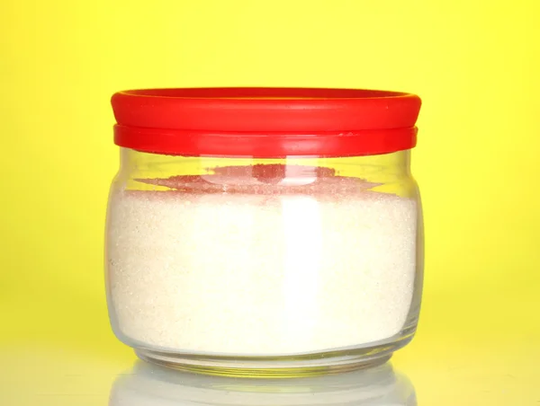 Frasco com açúcar de cristal branco sobre fundo colorido — Fotografia de Stock