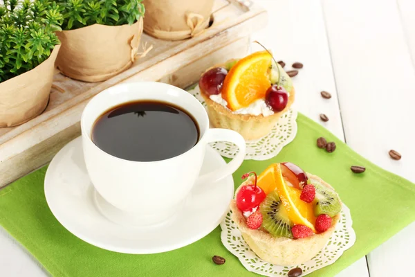 Taza de café y pasteles dulces con frutas en la mesa de madera — Foto de Stock
