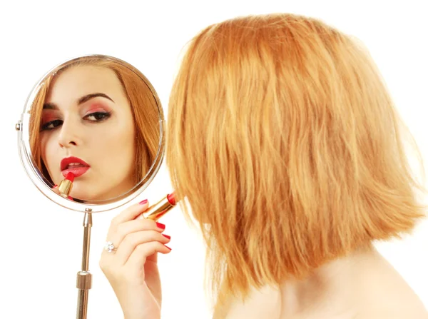 Schöne Frau trägt ihre Lippen mit rotem Lippenstift auf, sie blickt in den Spiegel — Stockfoto
