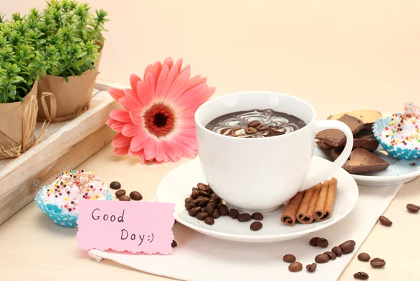 Kopp kaffe och gerbera bönor, kanel pinnar på träbord — Stockfoto