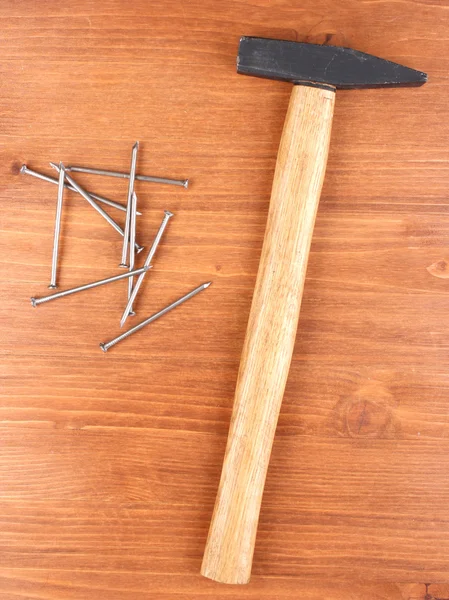 Martelo e unhas de metal no fundo de madeira — Fotografia de Stock