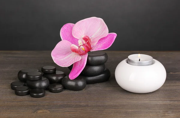 Pietre Spa con fiore di orchidea e candela su tavolo in legno su sfondo grigio — Foto Stock