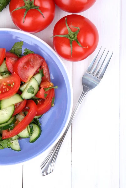 Frischer Salat mit Tomaten und Gurken auf weißem Holzgrund — Stockfoto