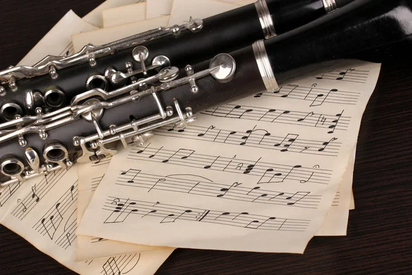 Музыкальные ноты и кларнет на деревянном столе — стоковое фото