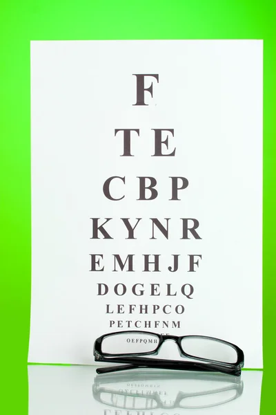 Gezichtsvermogen test grafiek met bril op groene achtergrond close-up — Stockfoto