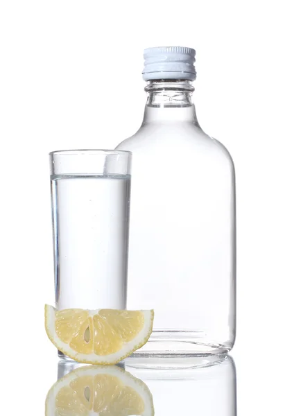 Bouteille de vodka et verre à vin au citron isolé sur blanc — Photo